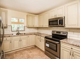 Renovated kitchen with light cabinets, stone-look counters, and tile backsplash