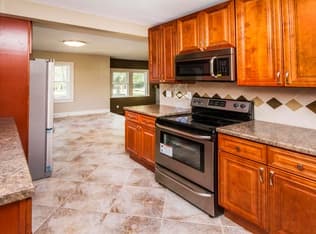 Renovated kitchen with wood cabinetry, tile floor, and updated appliances