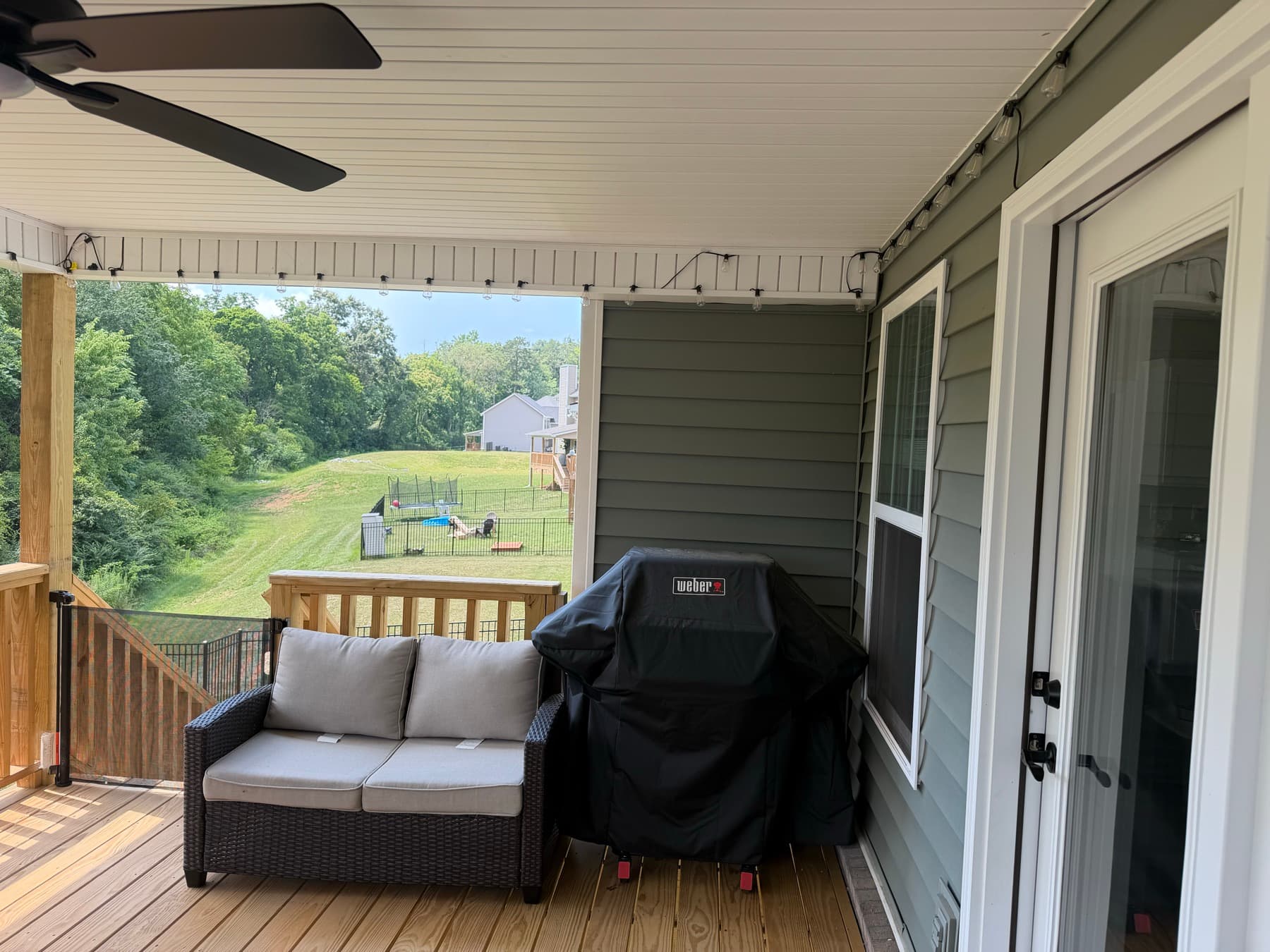 Covered deck seating and grill area beside the house
