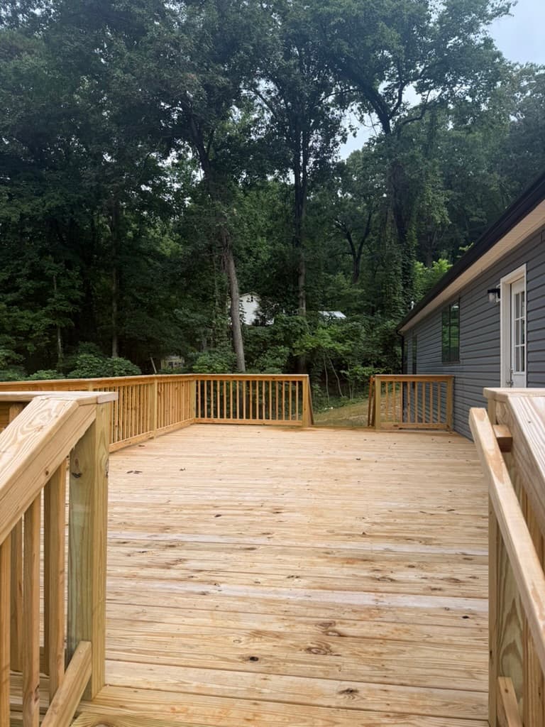 Wide completed rear deck overlooking the wooded property